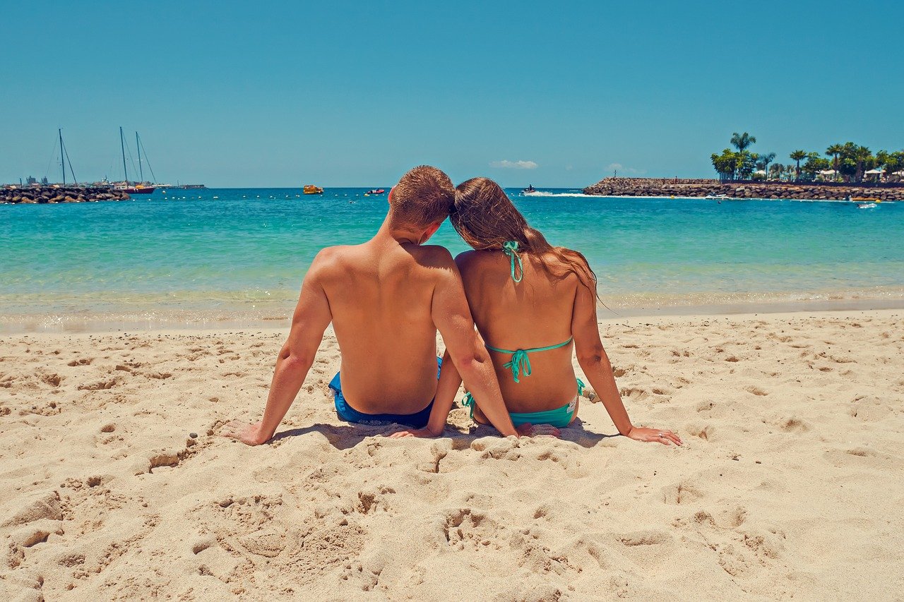 couple sitting next to each other on the beach